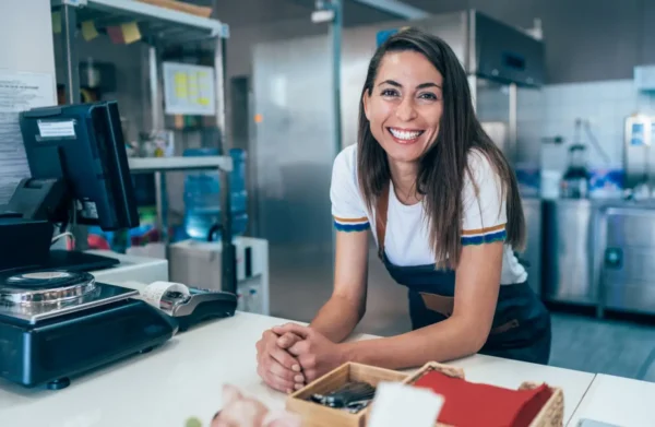 Entrepreneuse souriante dans son lieu de travail, représentant l'esprit entrepreneurial et la valorisation des initiatives locales.